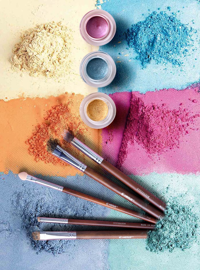 team-03 Colorful makeup powders and brushes in an artistic flat lay composition.