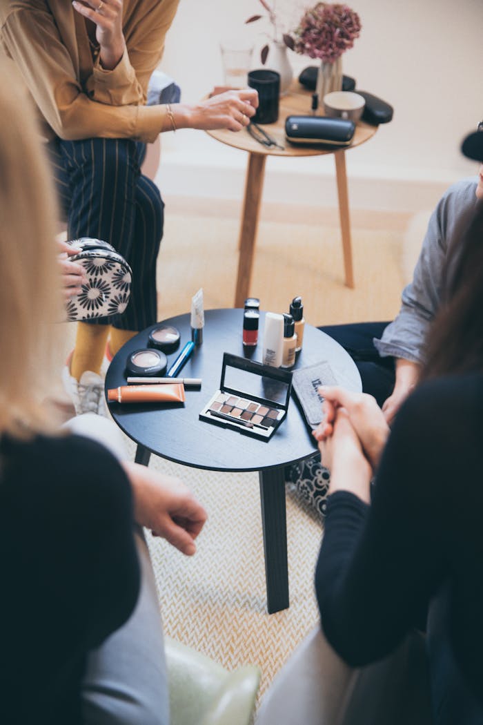 why-choose-us Women gathered around a table applying cosmetics, fostering a collaborative workspace.