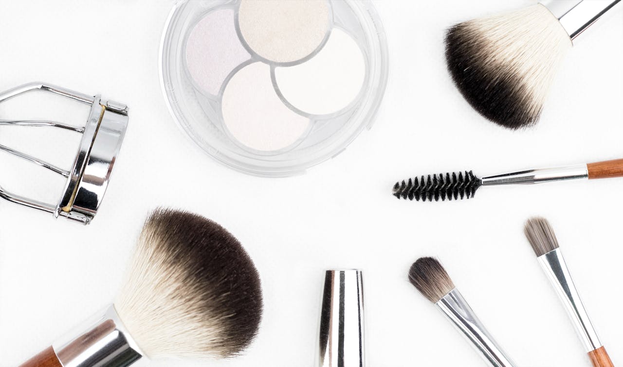 services-01 Flat lay of various makeup brushes and tools on a white background.