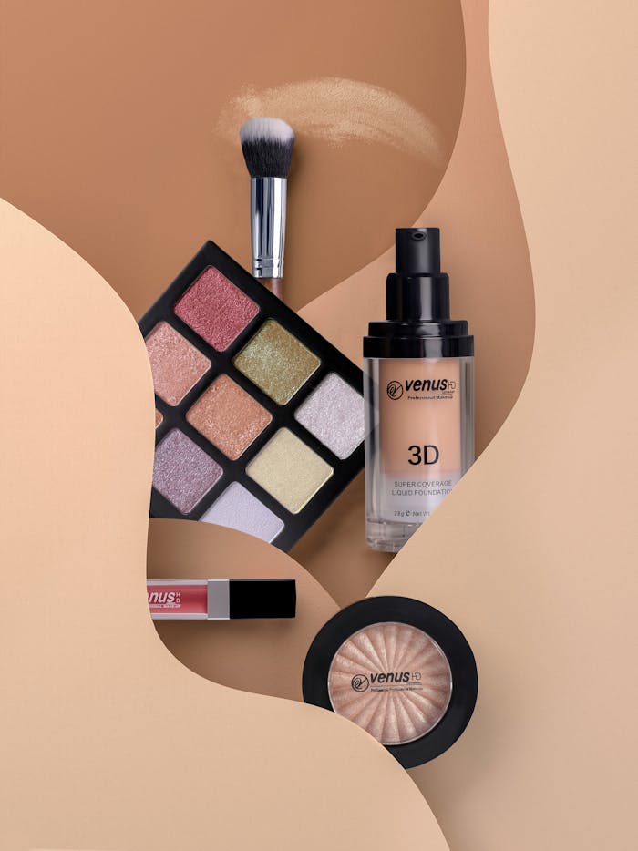 team-01 Flat lay of cosmetics including eyeshadow, lipstick, and blush with neutral tones.